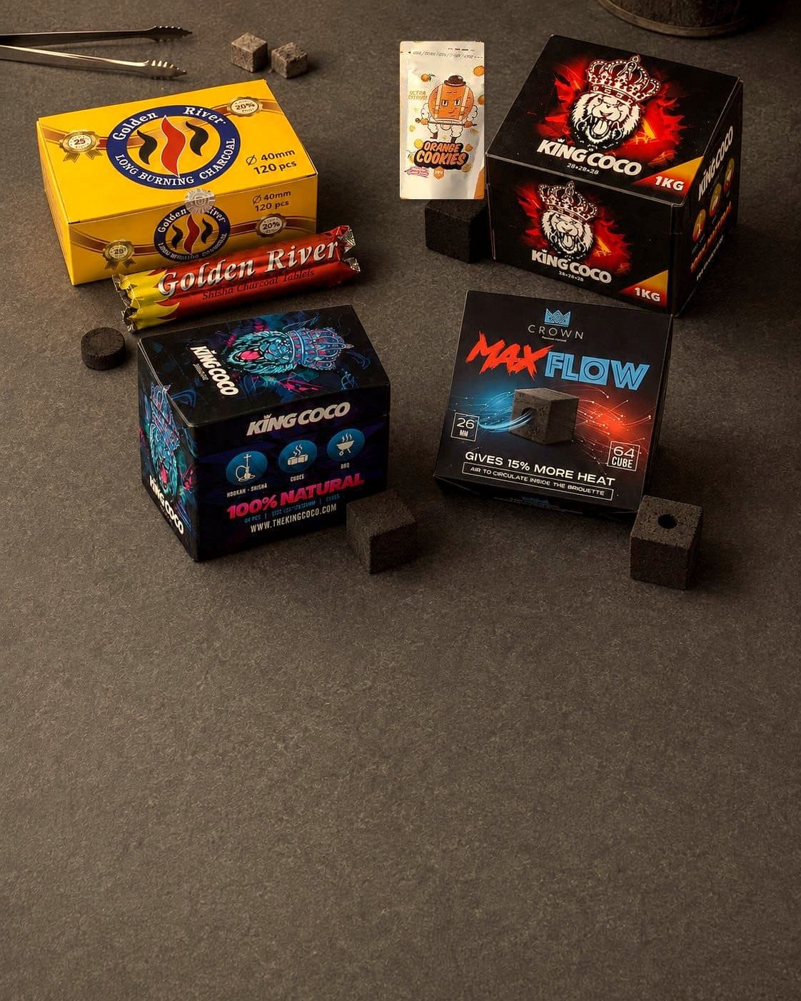Cajas de carbón King Coco, Golden River y Max Flow junto a piezas cúbicas, cilíndricas y perforadas sobre una superficie gris. Cajas de carbón King Coco, Golden River y Max Flow junto a piezas cúbicas, cilíndricas y perforadas sobre una superficie gris.