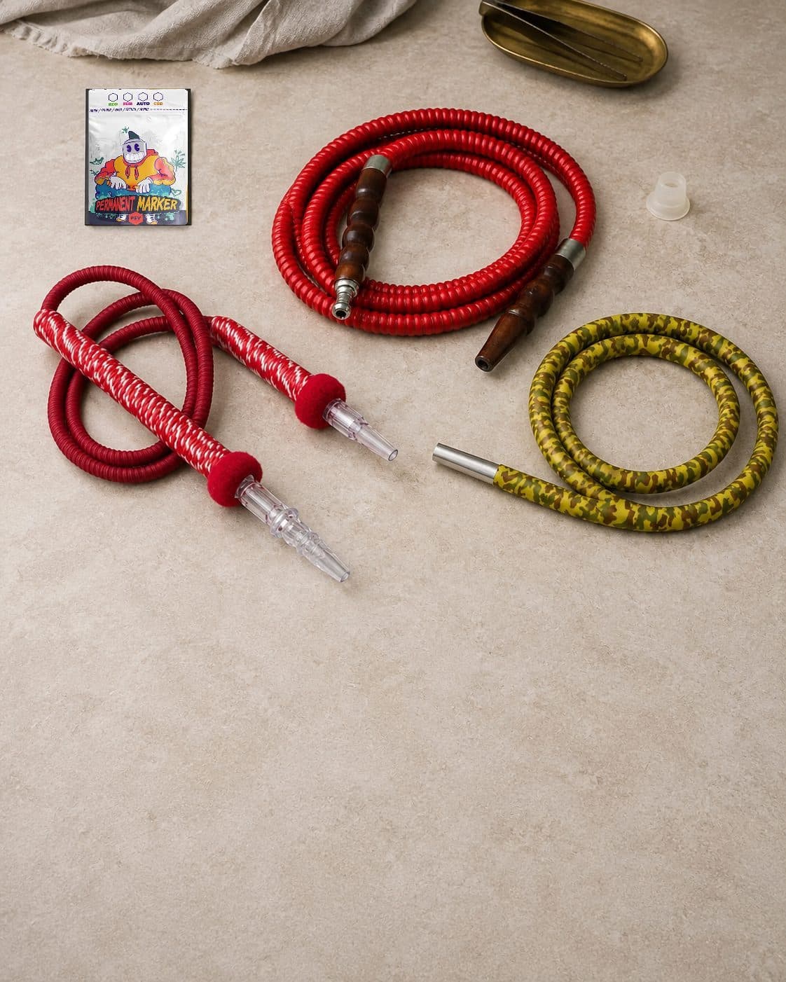 Tres modelos de mangueras de cachimba enrolladas: roja con mangos marrones, roja y blanca con boquillas transparentes y de camuflaje amarillo. Tres modelos de mangueras de cachimba enrolladas: roja con mangos marrones, roja y blanca con boquillas transparentes y de camuflaje amarillo.
