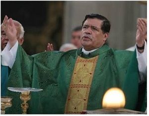 Sacerdote con vestimenta litúrgica verde y dorada, de pie ante el altar con ambos brazos levantados. Sacerdote con vestimenta litúrgica verde y dorada, de pie ante el altar con ambos brazos levantados.