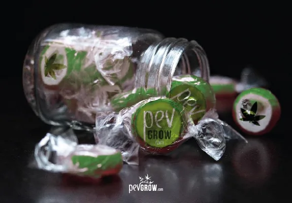 Caramelos redondos envueltos en plástico transparente junto a un tarro volcado, con motivos de hojas de cannabis y el nombre Pev Grow.