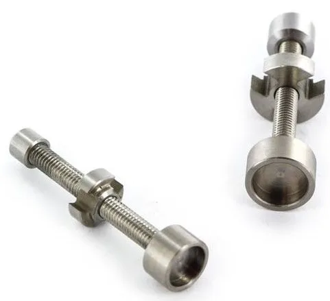Dos accesorios metálicos para dabbing con ejes roscados, tuercas y extremos cóncavos, dispuestos en diagonal sobre fondo blanco. Dos accesorios metálicos para dabbing con ejes roscados, tuercas y extremos cóncavos, dispuestos en diagonal sobre fondo blanco.