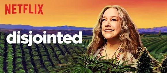 Cartel de Netflix de «Disjointed», con una mujer de pelo ondulado ante hileras de plantas y un cielo anaranjado.