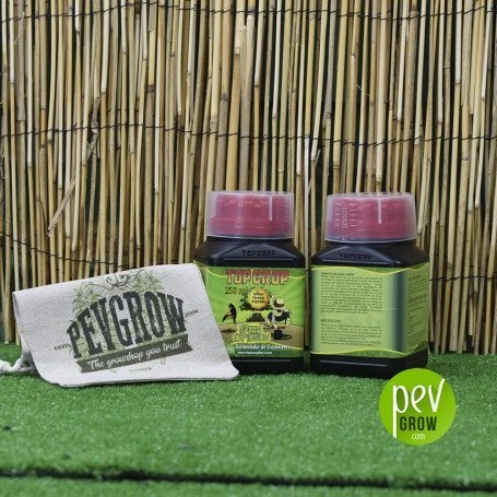 Dos botes de Top Crop con tapones rosas, uno de frente y otro de espaldas, junto a una bolsa Pevgrow sobre césped artificial.