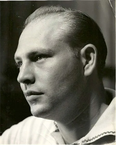 Retrato en blanco y negro de un hombre con el cabello peinado hacia atrás y camisa clara, mirando hacia la izquierda.