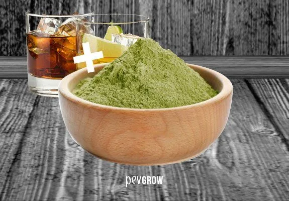 Cuenco de madera con polvo verde ante dos vasos con hielo y un signo de suma blanco, sobre una superficie de tablas grises.