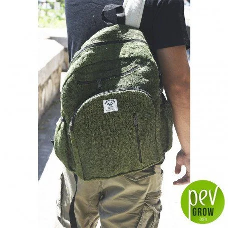 Persona de espaldas con mochila verde de textura jaspeada, bolsillo frontal con cremalleras y una etiqueta con una hoja.