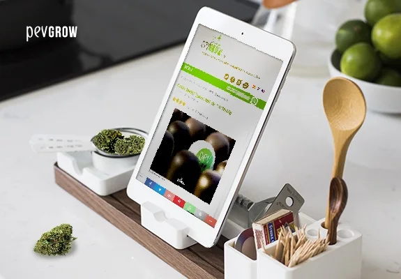 Tableta con una web de cocina sobre un soporte, junto a cogollos de cannabis, utensilios de cocina y un cuenco con limas. Tableta con una web de cocina sobre un soporte, junto a cogollos de cannabis, utensilios de cocina y un cuenco con limas.