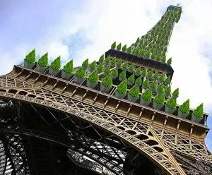 Montaje de la Torre Eiffel vista desde abajo, con plantas verdes distribuidas por sus plataformas y estructura superior.