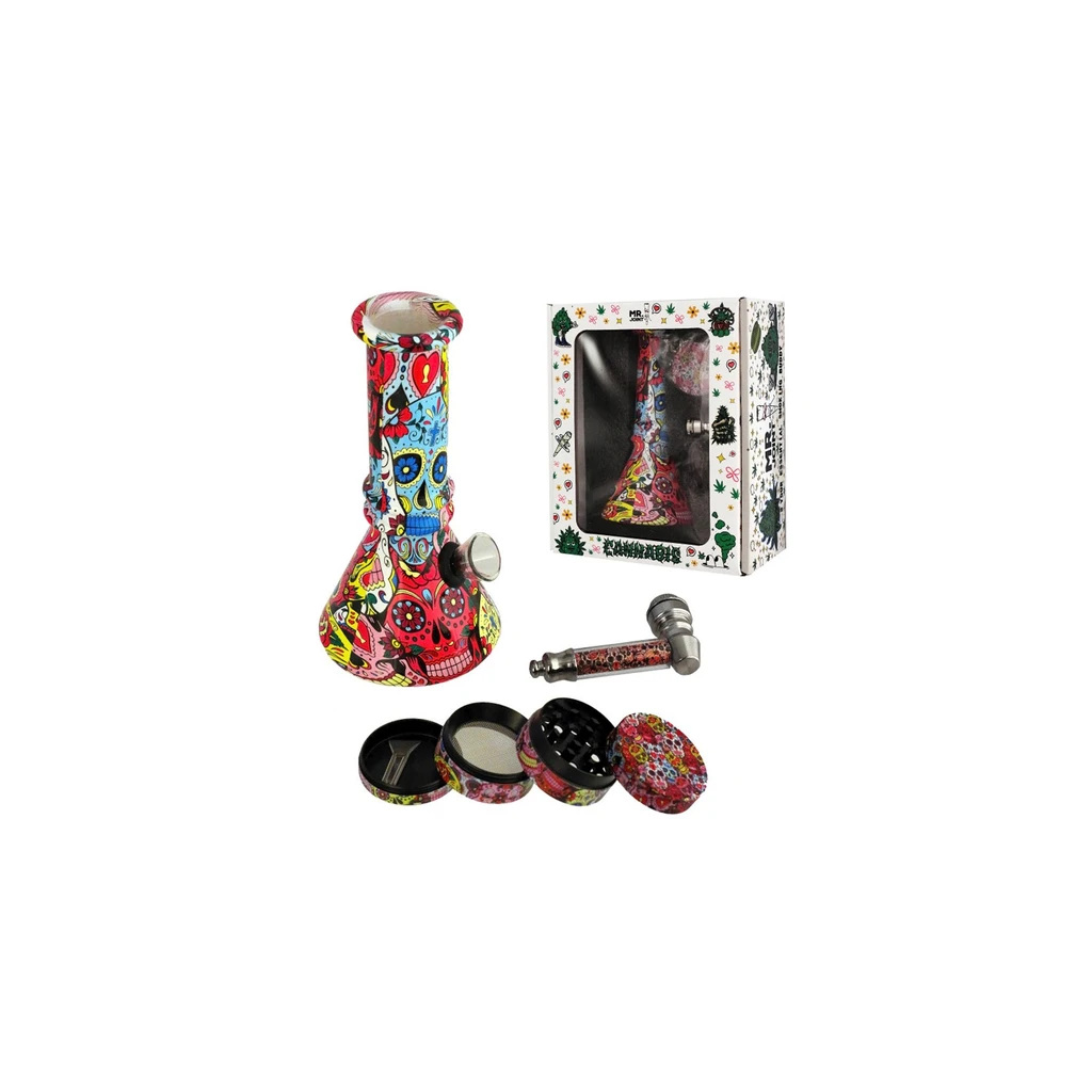 Bong con calaveras multicolores junto a una caja con ventana, una pipa y un grinder abierto con decoración a juego.