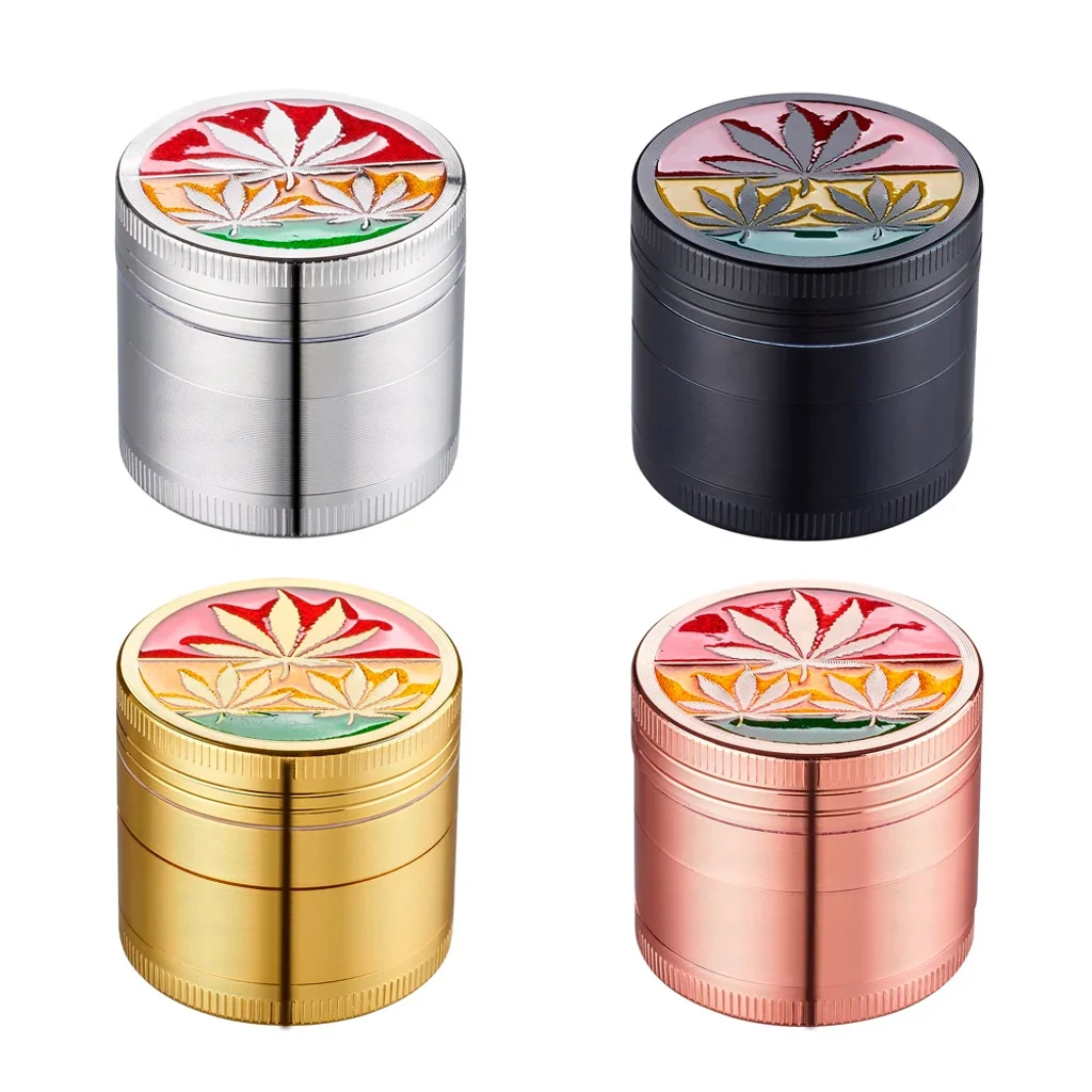 Grinders Leaf Rasta en acabados plateado, negro, dorado y rosado, con hojas de cannabis sobre franjas de colores en las tapas.