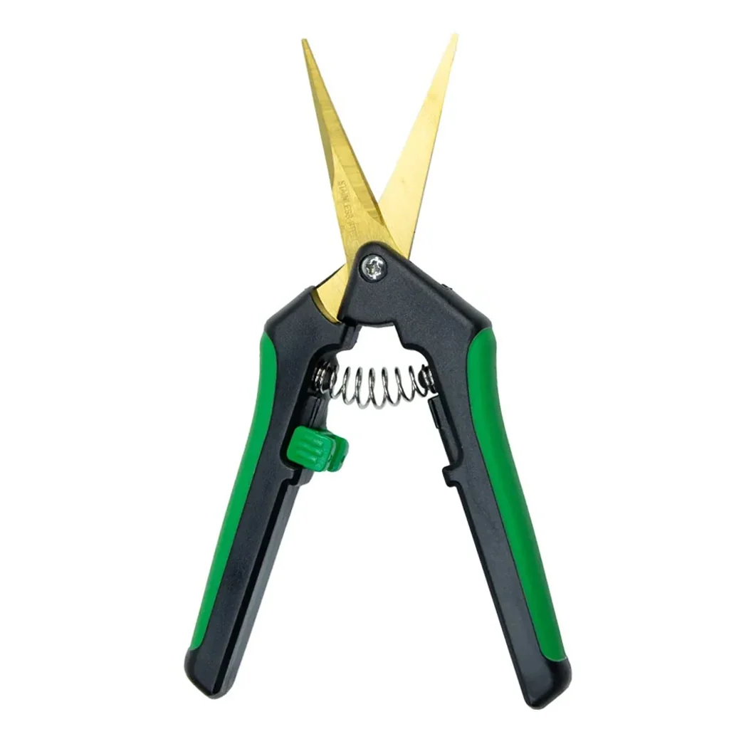 Tijera Titanium de punta recta abierta, con hojas doradas, mangos negros y verdes, muelle central y cierre verde.