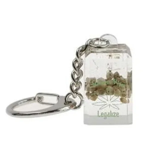 Llavero Semillitas con colgante rectangular transparente, pequeñas semillas en su interior y una hoja sobre el texto «Legalize».