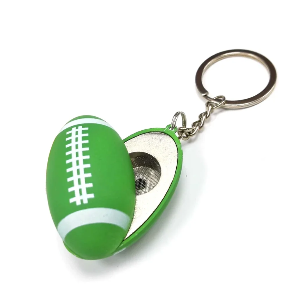 Pipa llavero con forma de balón de rugby verde y blanco, abierta para mostrar la cazoleta metálica con rejilla.