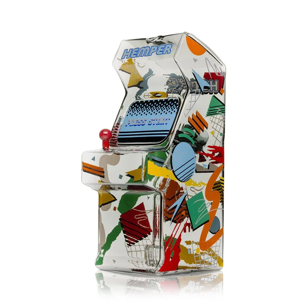 Bong HEMPER Totally Rad Arcade XL con forma de máquina recreativa, palanca roja y motivos geométricos multicolores sobre cuerpo transparente.