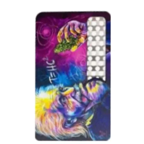 Grinder en formato de tarjeta, con ilustración multicolor de un rostro y una mano, y franja metálica perforada en un lateral. Grinder en formato de tarjeta, con ilustración multicolor de un rostro y una mano, y franja metálica perforada en un lateral.