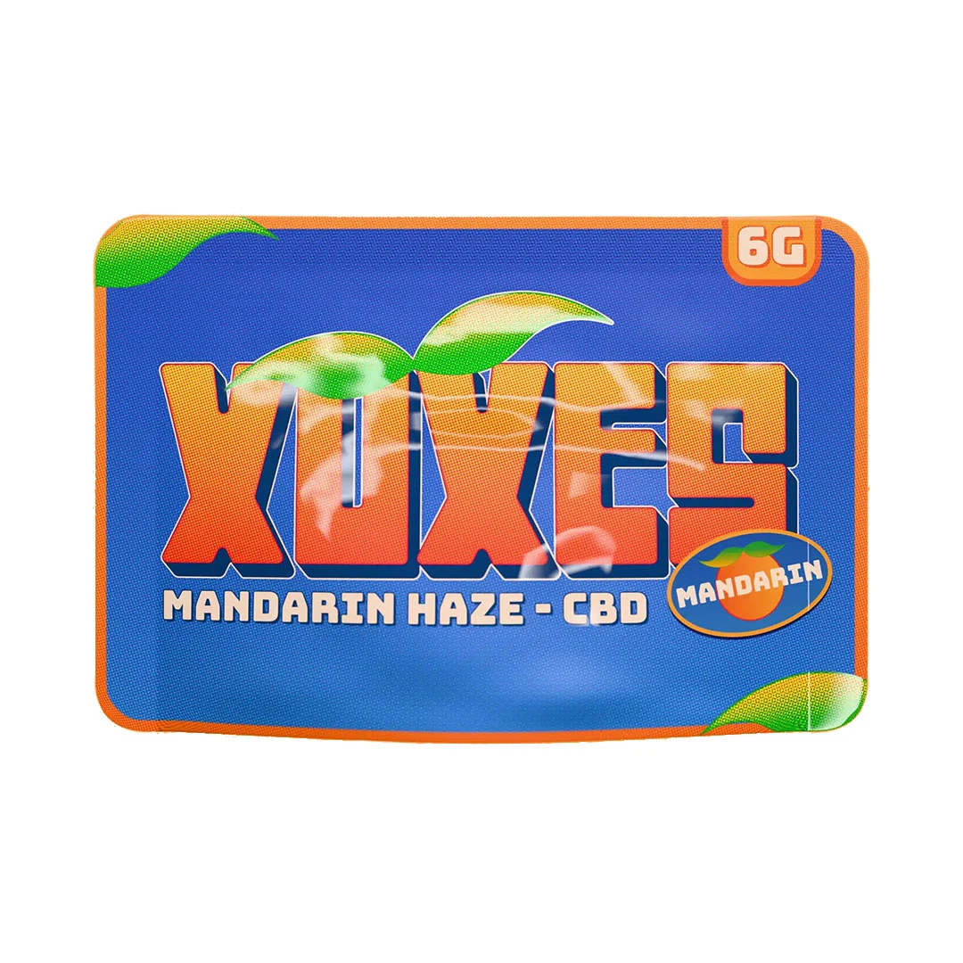 Envase azul con bordes naranjas de Xuxes Mandarin Haze CBD, con letras grandes, dibujos de hojas y mandarina e indicación de 6 g.