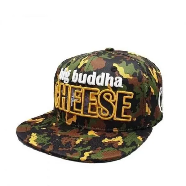 Gorra de camuflaje con visera plana y bordado frontal «big buddha CHEESE» en blanco y amarillo, vista en tres cuartos.