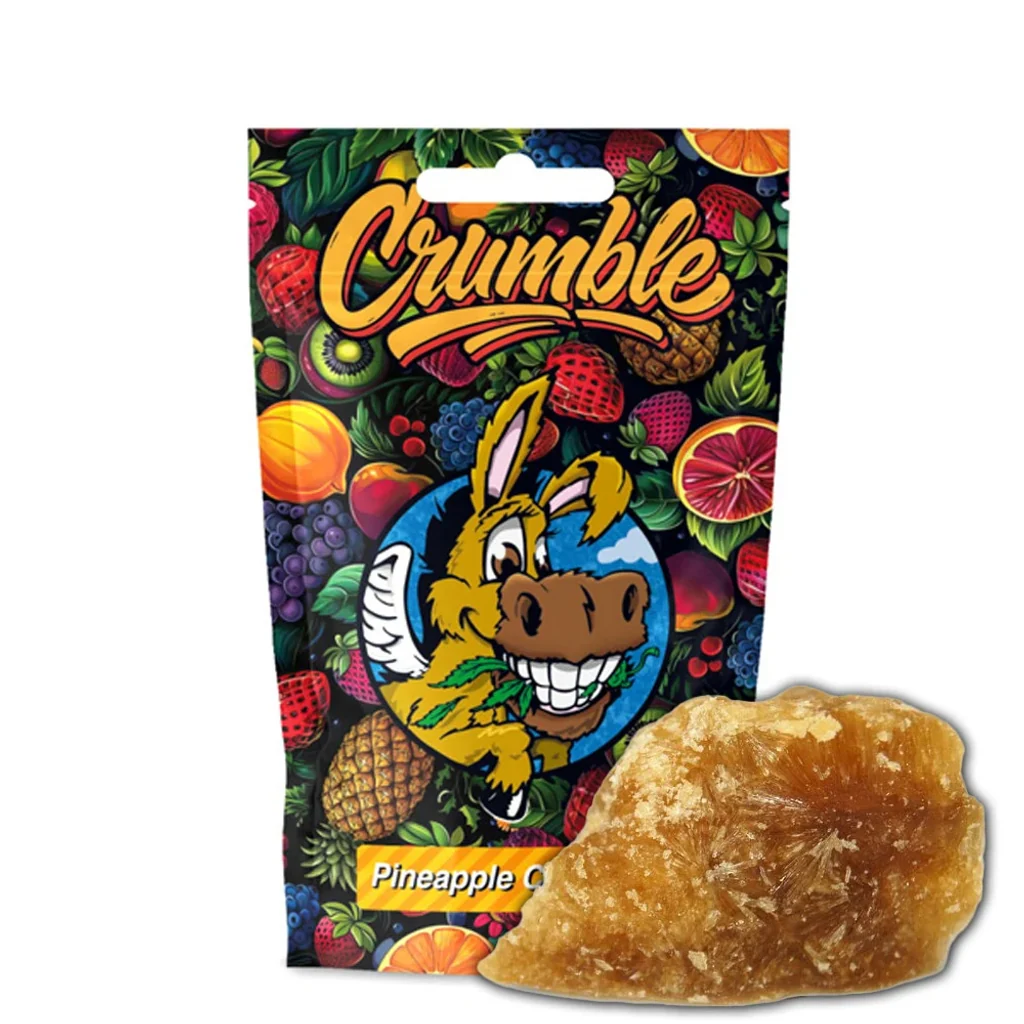Crumble Flying Burrito Pineaple Crush de tono ámbar ante una bolsa ilustrada con frutas y un burro sonriente bajo el rótulo Crumble.