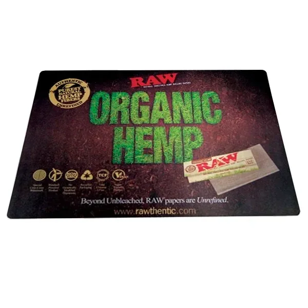 Alfombrilla rectangular RAW con fondo oscuro, texto verde «Organic Hemp» y dibujo de un librillo de papel de fumar en la esquina inferior.