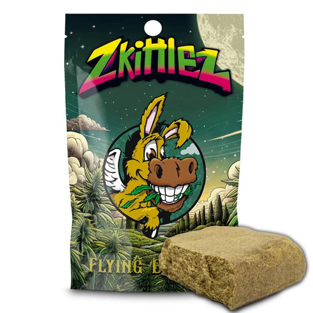 Bloque de hachís CBD Flying Burrito Zkittlez ante una bolsa verde con letras multicolor y un burro de dibujos.