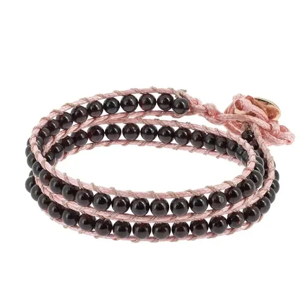 Pulsera Naga Granate Tierra Zen de varias vueltas, con cuentas oscuras brillantes, cordón rosa y cierre de botón sobre fondo blanco. Pulsera Naga Granate Tierra Zen de varias vueltas, con cuentas oscuras brillantes, cordón rosa y cierre de botón sobre fondo blanco.