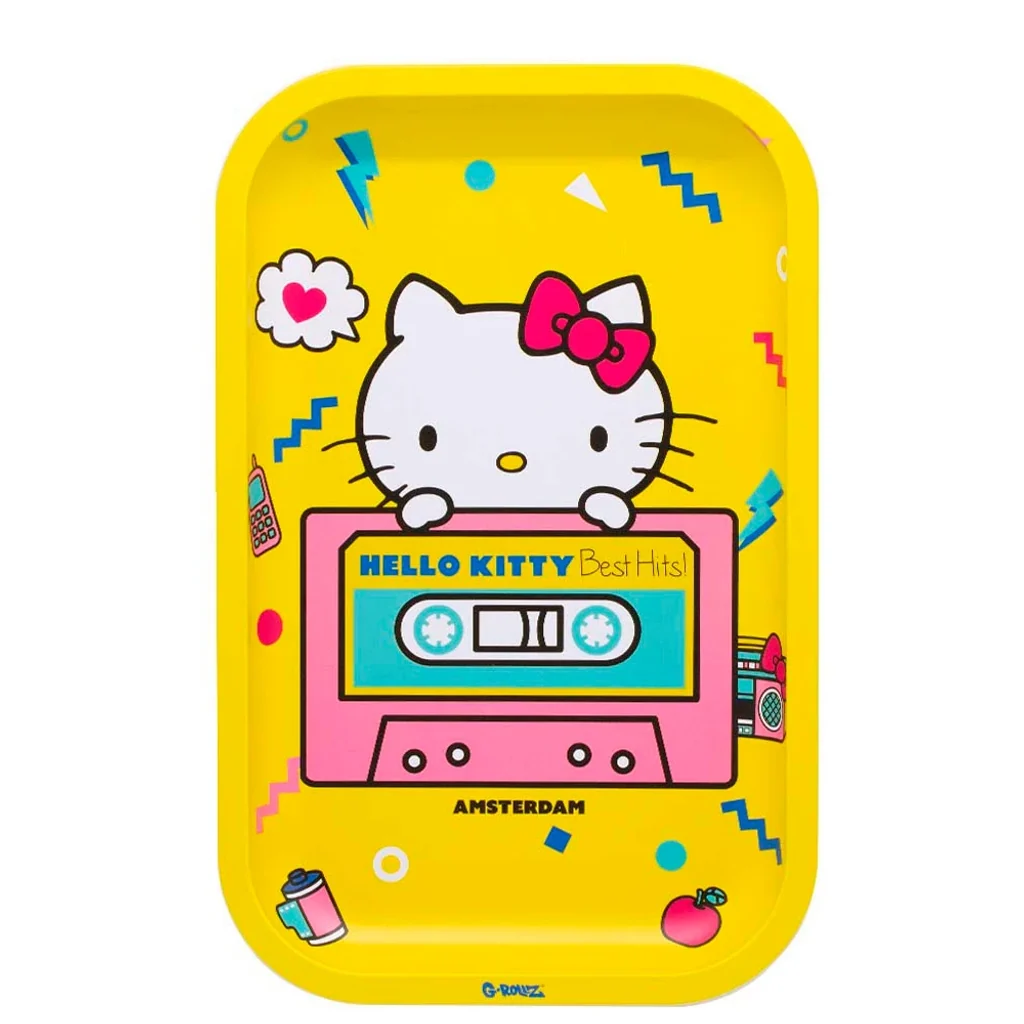 Bandeja amarilla G-Rollz con Hello Kitty tras un casete rosa y turquesa, texto «Hello Kitty Best Hits!» y pequeños motivos musicales.