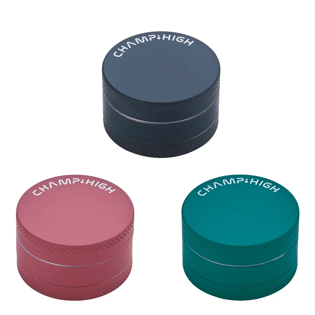 Grinders Champ High cerrados en distintos colores: gris oscuro, rosa y verde azulado, con bordes texturizados y logotipo en la tapa. Grinders Champ High cerrados en distintos colores: gris oscuro, rosa y verde azulado, con bordes texturizados y logotipo en la tapa.