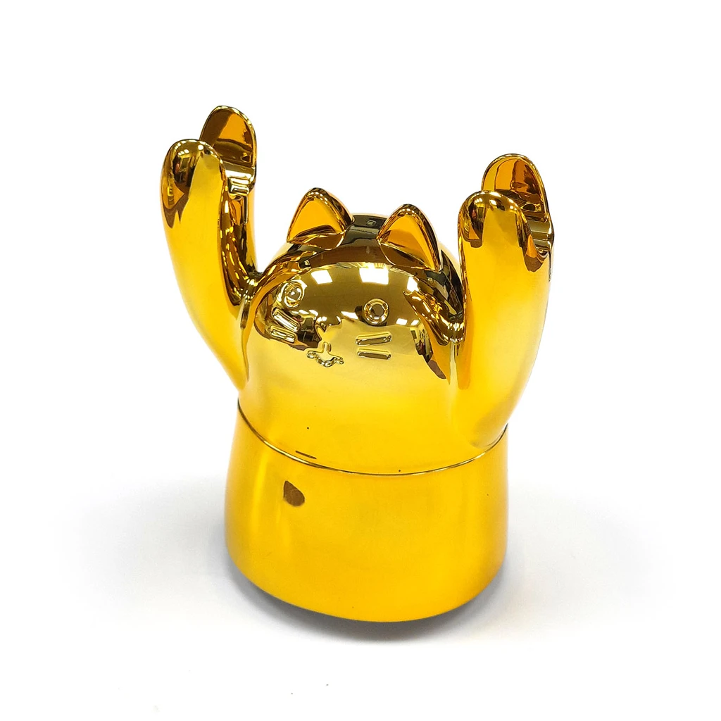 Grinder Polinizador Gold Cat dorado y brillante, con rostro de gato, orejas puntiagudas y patas levantadas sobre una base cilíndrica.