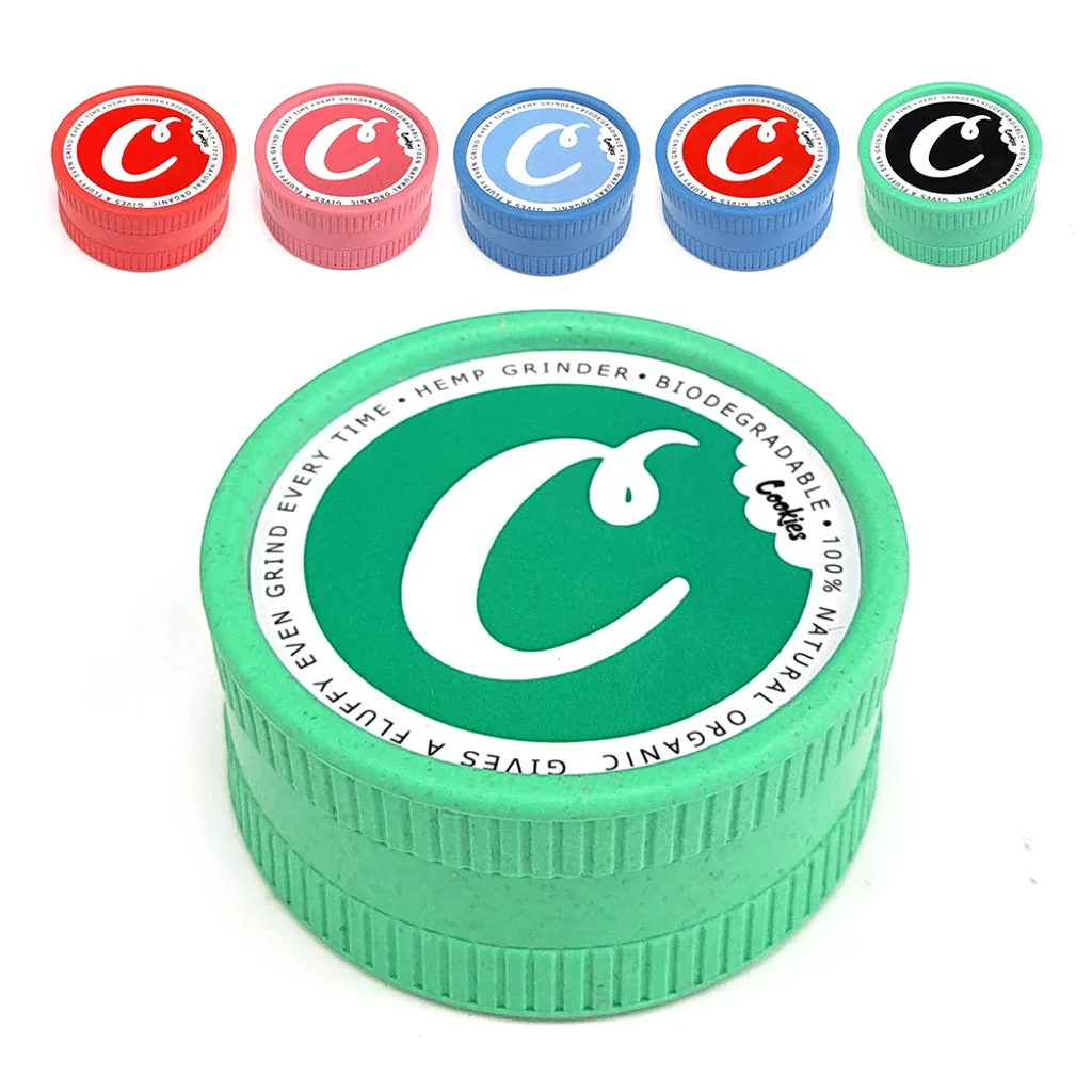 Grinder Cookies verde en primer plano, con bordes estriados y logotipo en la tapa; arriba se muestran variantes de varios colores.