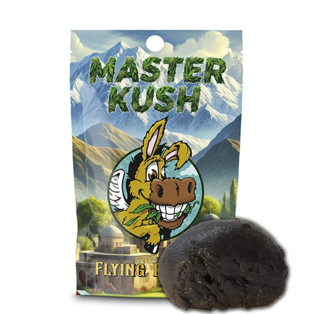 CBD Hash Flying Burrito Master Kush: pieza oscura ante un envase con montañas y un burro ilustrado bajo el nombre Master Kush.