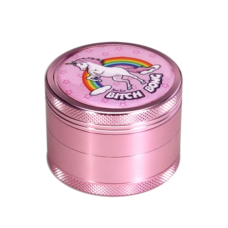 Grinder Bitch Bong rosa, cerrado y visto en perspectiva, con bordes estriados y un unicornio blanco sobre un arcoíris en la tapa.