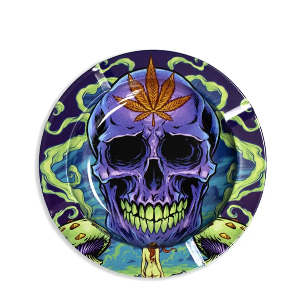 Cenicero circular con calavera morada, dientes verdes y una hoja de cannabis en la frente, rodeada de volutas verdes.