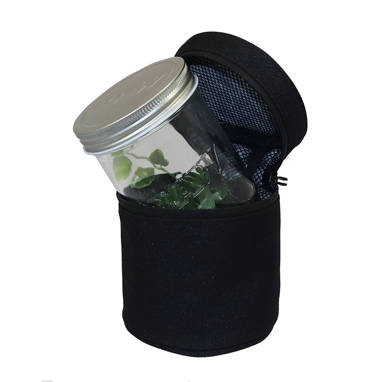 Tarro Raw Jar Mason transparente con tapa metálica, inclinado dentro de una funda negra abierta con cremallera y bolsillo de malla.