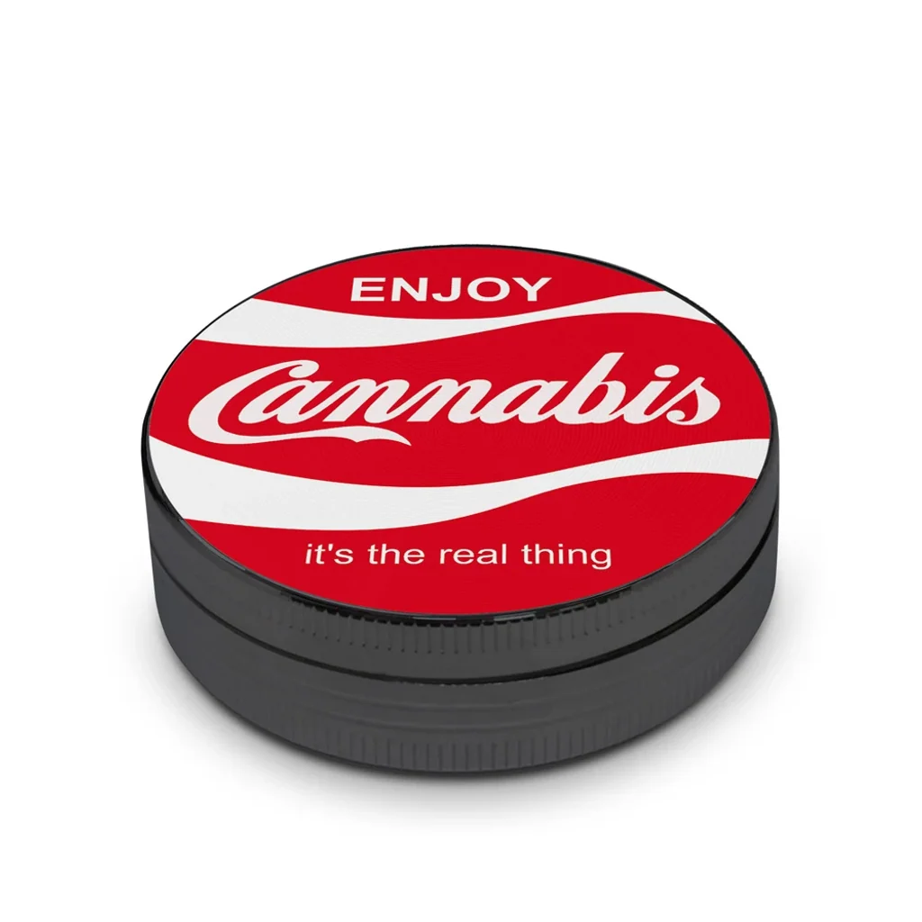 Grinder redondo negro con tapa roja, ondas blancas y el texto «Enjoy Cannabis, it's the real thing», visto en perspectiva.