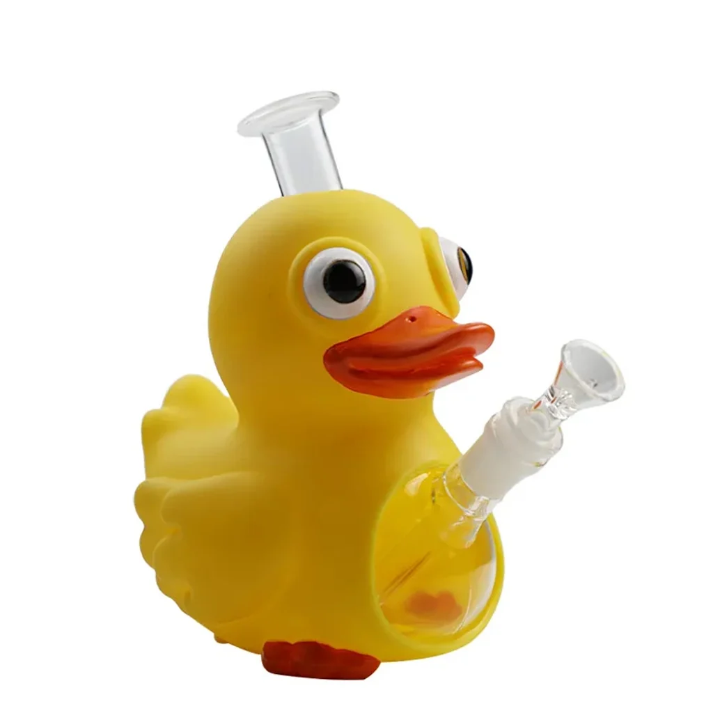 Bong con forma de pato amarillo, pico naranja y ojos saltones, con boquilla transparente superior y cazoleta lateral sobre fondo blanco.