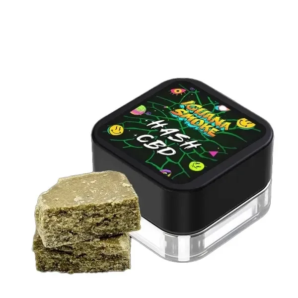 Hash CBD Iguana Smoke Caramel en bloques de tono verdoso y textura granulada junto a un recipiente con tapa negra rotulada Hash CBD.