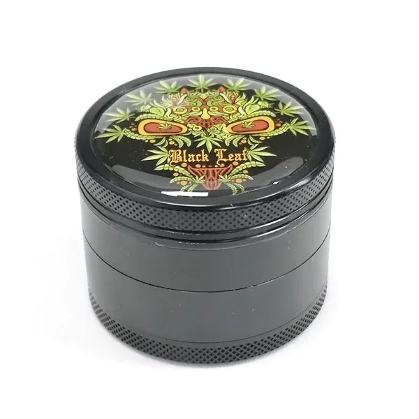 Grinder Black Leaf oscuro y cilíndrico, con bordes texturizados y una calavera de colores formada por hojas en la tapa.