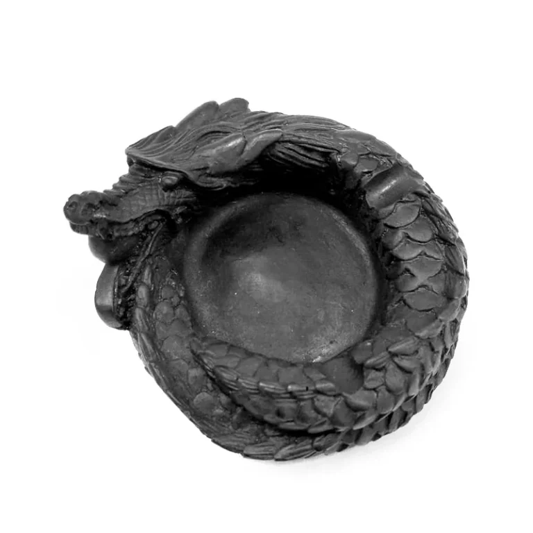 Cenicero negro con un dragón enroscado alrededor del cuenco central, cabeza en relieve y escamas marcadas sobre fondo blanco.