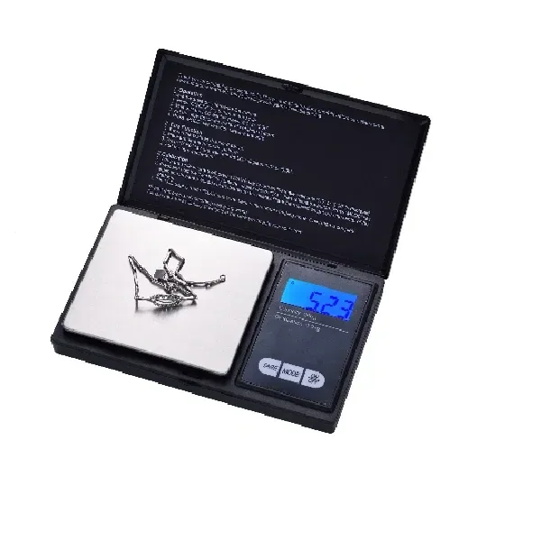 Báscula digital Champ High abierta, con objetos metálicos sobre la plataforma y pantalla azul que marca 5.23.