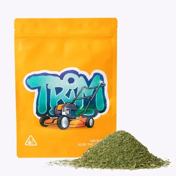 Bolsa naranja con el texto «TRIM» y una cortadora de césped dibujada, junto a un montón de material vegetal triturado.