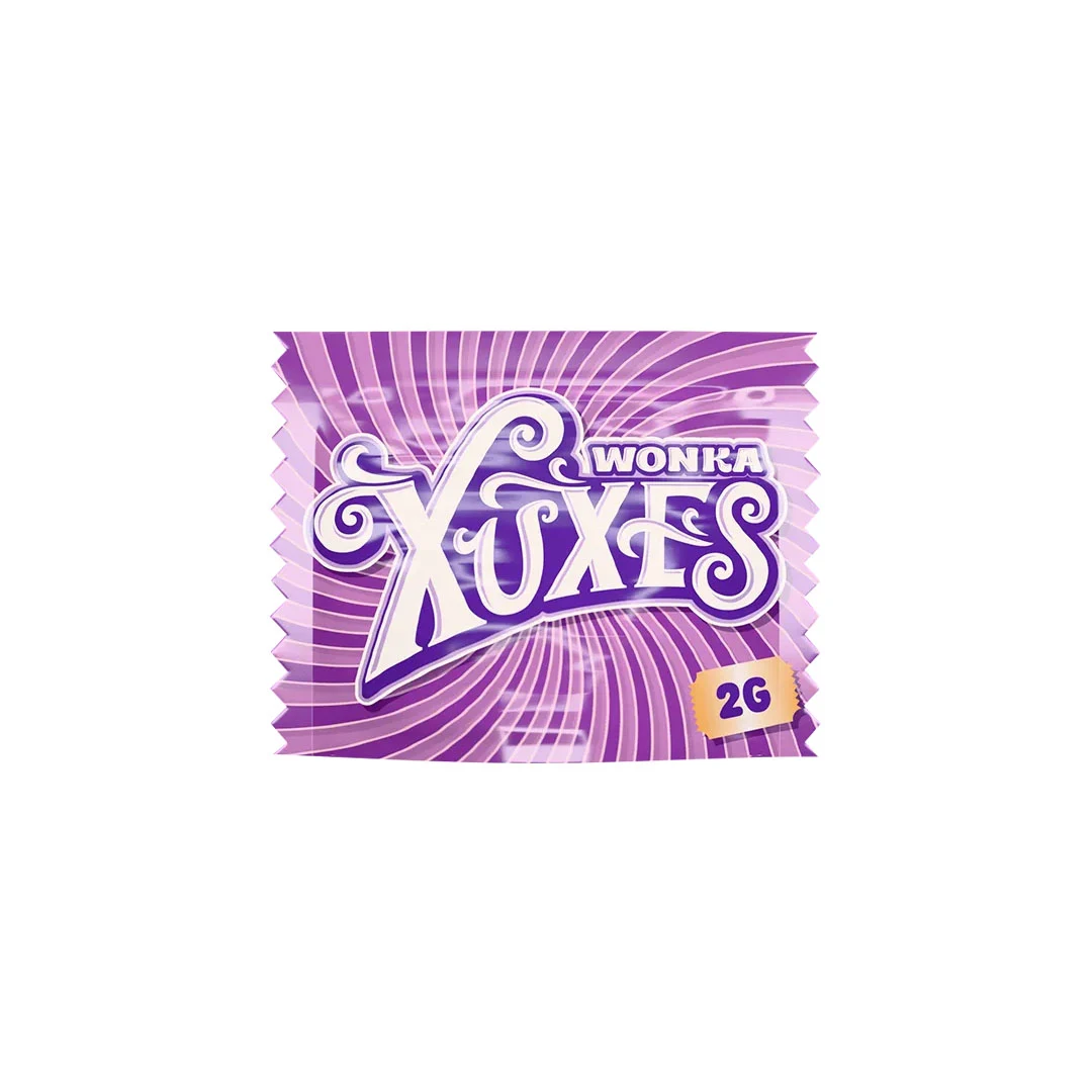 Envoltorio morado de Hash CBD Xuxes Wonka con líneas onduladas, letras blancas grandes y distintivo amarillo con el texto 2G.