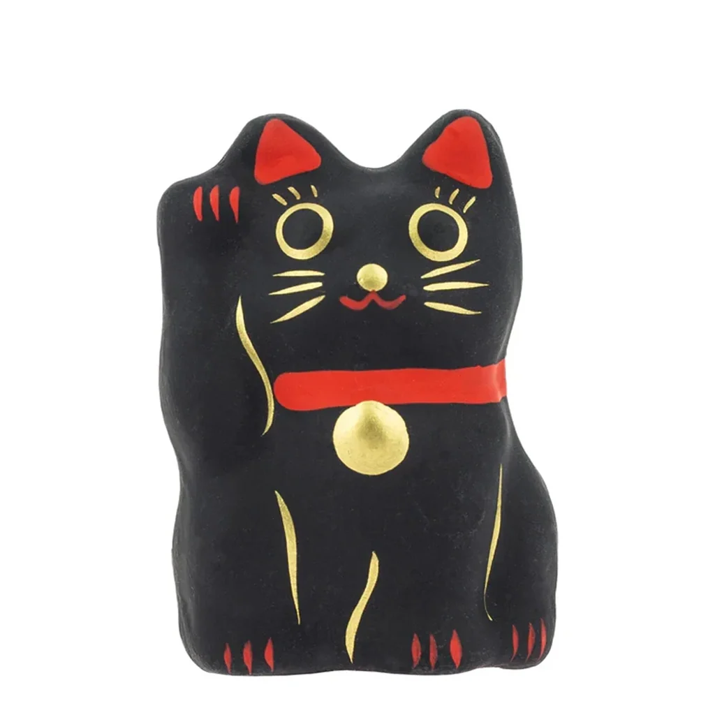 Figura de gato Maneki Neko Kuro negro, de frente con una pata levantada, detalles dorados y orejas y collar rojos sobre fondo blanco. Figura de gato Maneki Neko Kuro negro, de frente con una pata levantada, detalles dorados y orejas y collar rojos sobre fondo blanco.