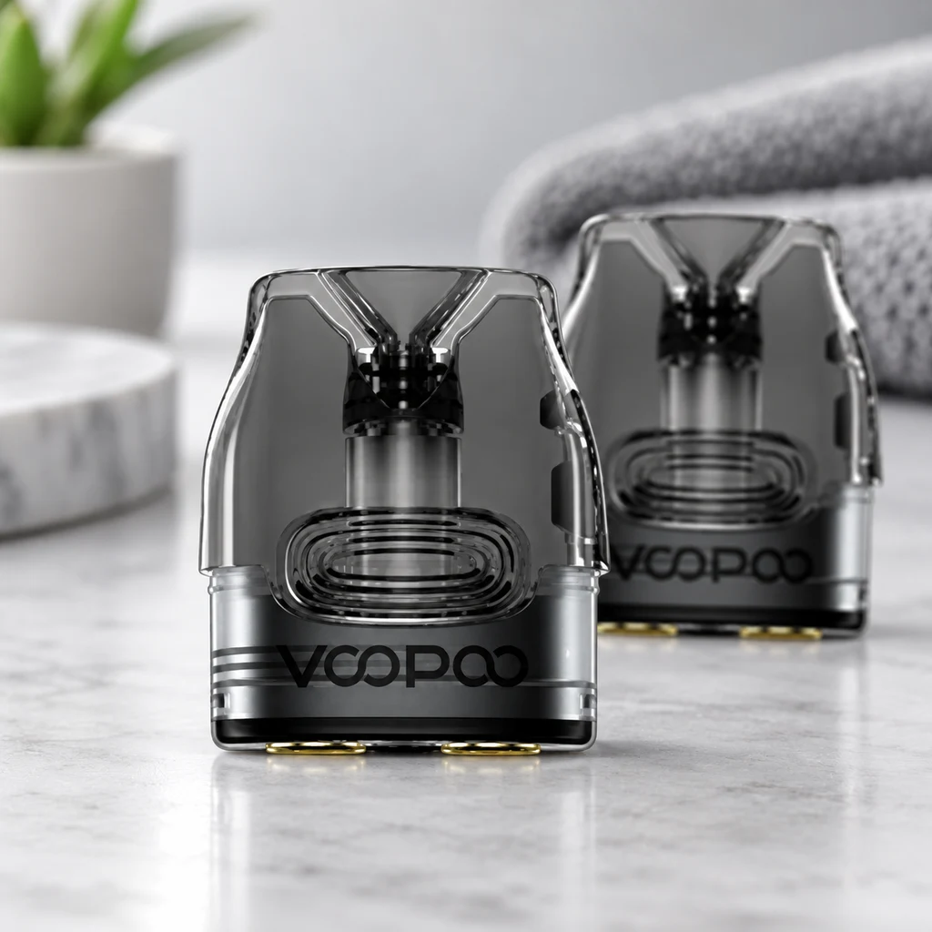 Cartuchos Voopoo VMate translúcidos oscuros sobre una superficie clara, con uno en primer plano y otro detrás. Cartuchos Voopoo VMate translúcidos oscuros sobre una superficie clara, con uno en primer plano y otro detrás.