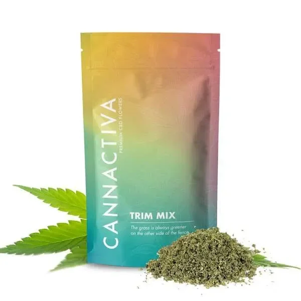 Bolsa multicolor de TRIM MIX Cannactiva con un montón de cáñamo picado delante y hojas verdes a los lados sobre fondo blanco.
