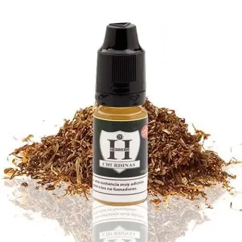Frasco de Herrera Churdinas con tapón negro y etiqueta blanca, delante de un montón de tabaco picado sobre una superficie reflectante.