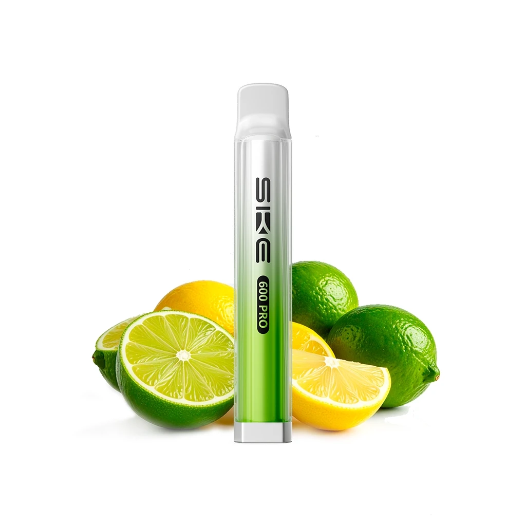 Dispositivo SKE Crystal 600 Pro Lemon Lime de cuerpo verde y transparente, con boquilla blanca, delante de limones y limas enteros y cortados.