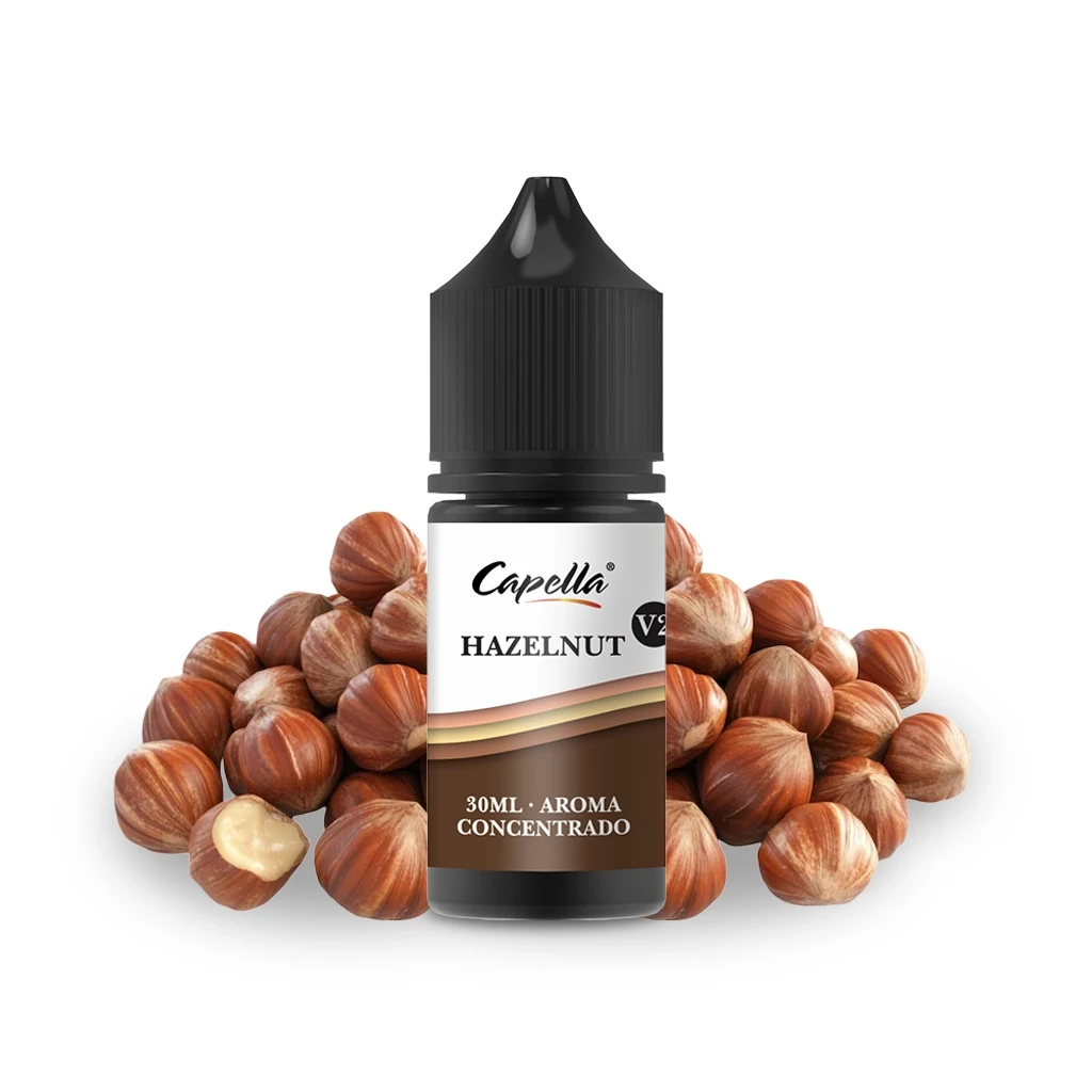 Frasco de aroma Capella Hazelnut V2 con tapón negro y etiqueta marrón y blanca, rodeado de avellanas sobre fondo blanco.