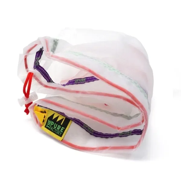 Bolsa de extracción Pure Factory plegada, de malla blanca translúcida con ribetes rojos, cintas moradas y cierre de cordón rojo. Bolsa de extracción Pure Factory plegada, de malla blanca translúcida con ribetes rojos, cintas moradas y cierre de cordón rojo.