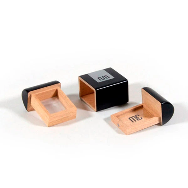 Caja FUM Pocket desmontada sobre fondo blanco, con carcasa negra y piezas de madera clara dispuestas a ambos lados.