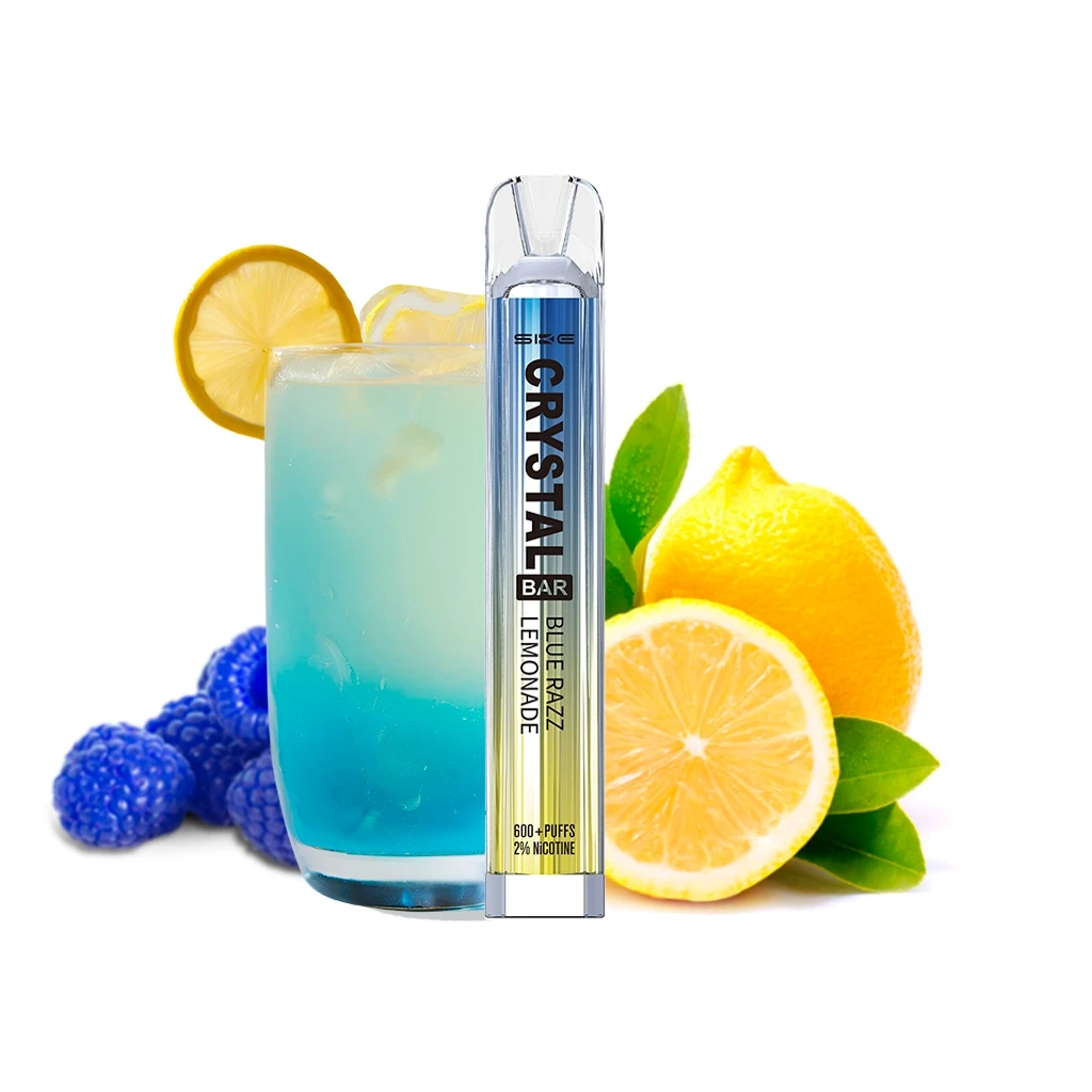 Vaper SKE Crystal Bar Blue Razz Lemonade en vertical, delante de un vaso con bebida azul, limones y frutos azules sobre fondo blanco.